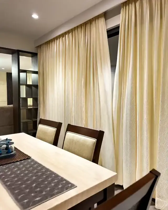 A dining table and upholstered chairs beside full height curtains
