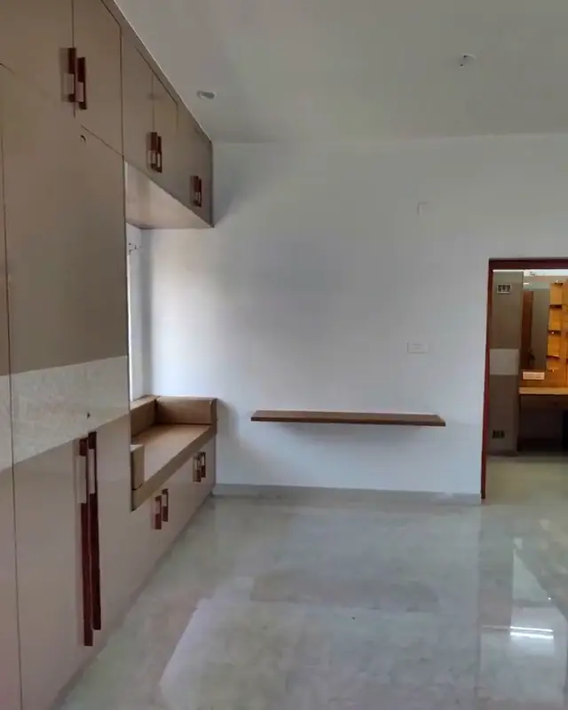 A bedroom wall of full-height wardrobes beside a built in window ledge